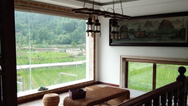 A room with a large window overlooking a green landscape, a wooden bench, and a hanging lantern. - Xianju Stomping Songs Homestay (Xianju)