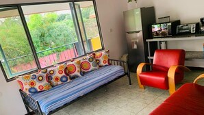 A room with a sofa bed, a red chair, a microwave, and a refrigerator. - MONKEY VIEW: Relaxed Quiet Secure Get Away from the Pto Viejo party + Location!  (Puerto Viejo de Talamanca)