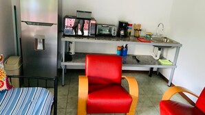 A compact room with a bed, a red chair, a small kitchenette, and a refrigerator. - MONKEY VIEW: Relaxed Quiet Secure Get Away from the Pto Viejo party + Location!  (Puerto Viejo de Talamanca)