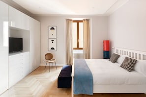 Um quarto com uma cama, uma cadeira, uma televisão e um radiador.