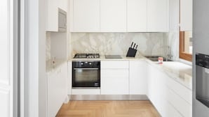 A compact kitchen with white cabinets, a built-in oven, a gas stove, and a sink. - Apartments Florence - The Wizard's House (Firenze)