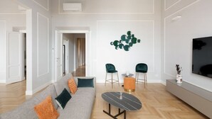 A modern living room with a sofa, two chairs, a coffee table, and a wall-mounted TV. - Apartments Florence - The Wizard's House (Firenze)