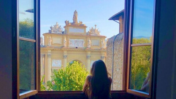 A room with a large window offering a view of a historic building with statues and ornate architecture. - Apartments Florence - The Wizard's House (Firenze)