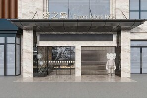 El exterior del Hotel Dream Island, con fachada de mármol, una amplia entrada de vidrio y una estatua de oso al frente.