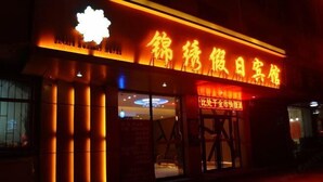 Un edificio con señalización iluminada en un idioma extranjero, grandes ventanales y una lámpara destacada sobre la entrada.