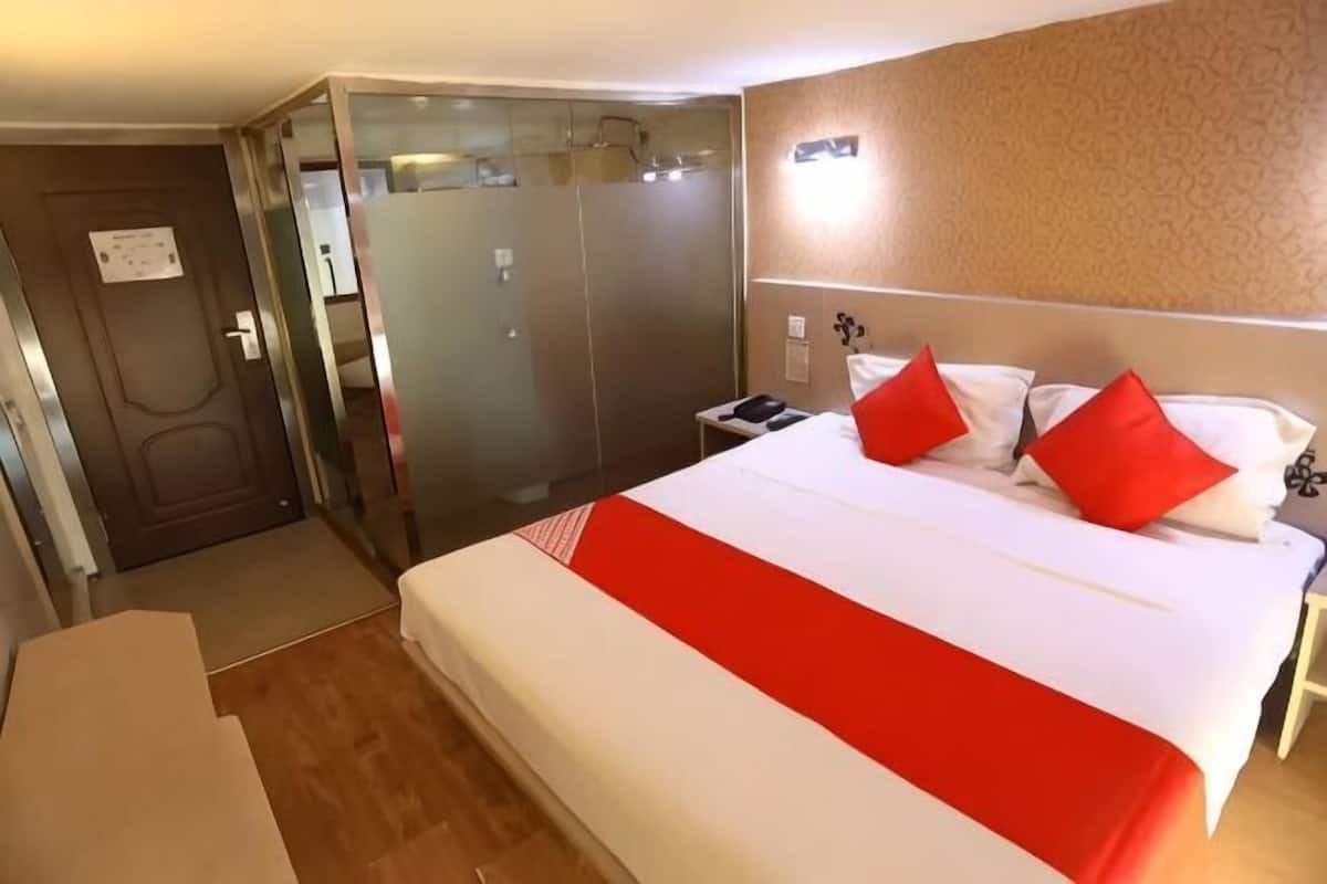 A hotel room with a bed, a desk, a wardrobe, and a mirror.