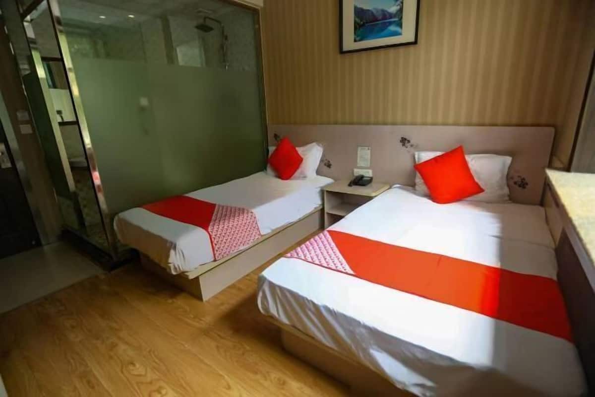 A hotel room with two beds, each with a red and white bedspread, a nightstand with a phone, and a painting on the wall.