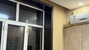 Una habitación con un ventanal grande, un equipo de aire acondicionado instalado en la pared y una puerta visible.