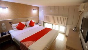 Una habitación de hotel con cama, mesita de noche, escritorio, radiador y televisión.
