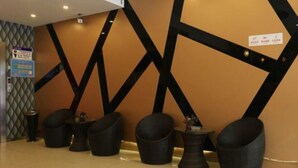 A reception area with a modern design, featuring a geometric wall pattern, a reception desk, and several seating options. - Splendid Holiday Hotel (Mudanjiang)