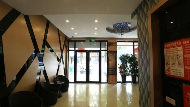 Un vestíbulo de hotel de diseño moderno, con un patrón geométrico en la pared, una araña y una entrada con puerta de cristal.