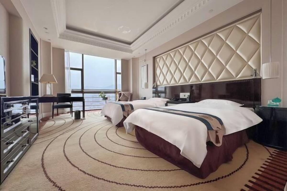 Une chambre d’hôtel avec deux lits, un bureau et une grande fenêtre.