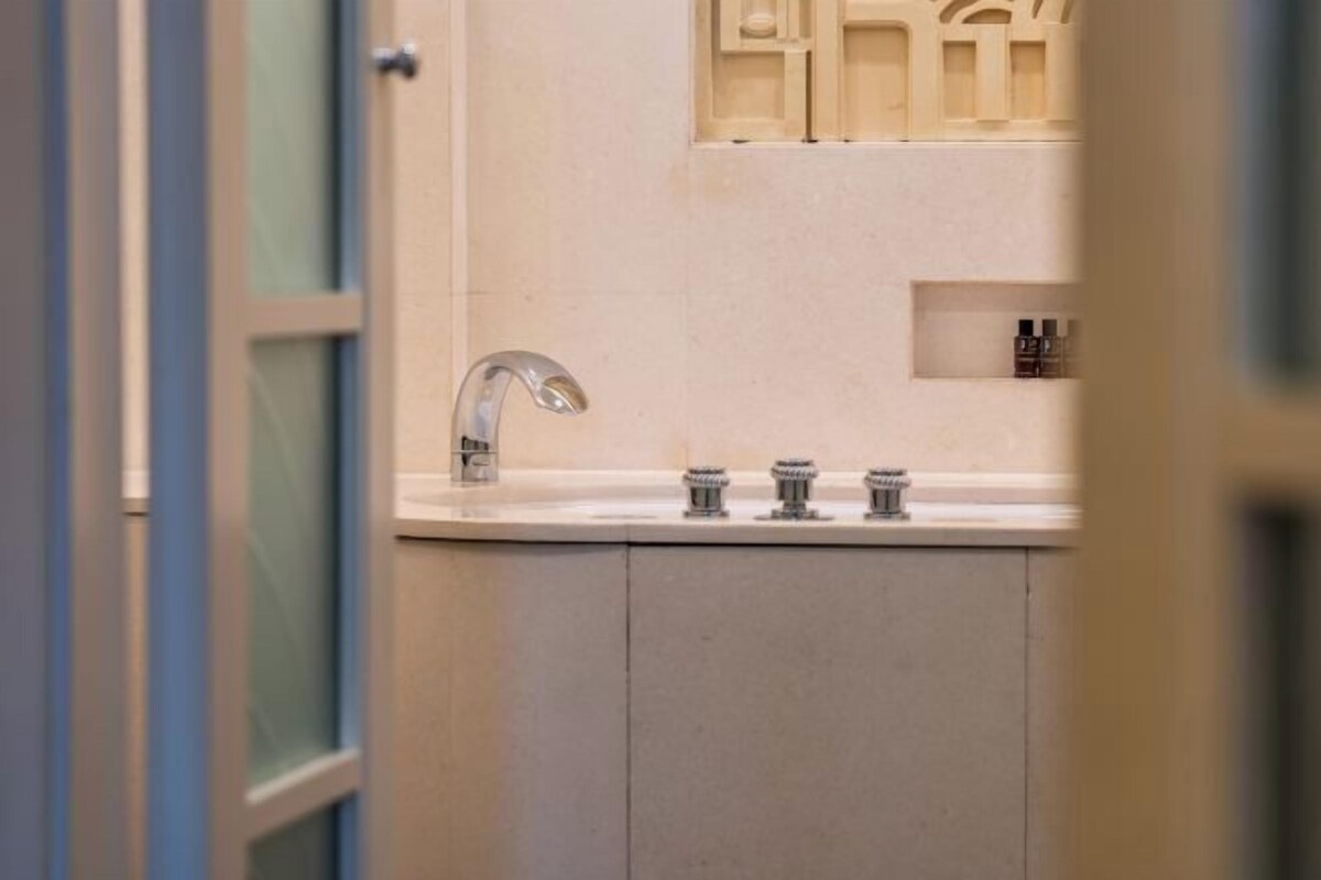 Un baño con lavamanos, espejo y mueble con artículos de aseo.
