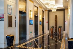 Un moderno vestíbulo de hotel con piso de mármol, ascensores e iluminación decorativa.