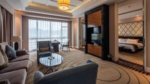 A modern hotel room with a sofa, a round coffee table, a TV, and a bed with a headboard. - Zhaofeng International Hotel (Kuancheng)