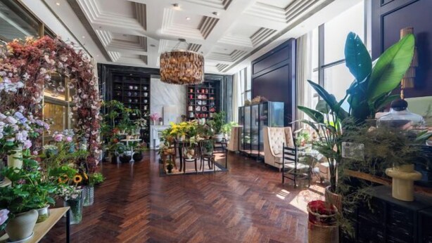 A spacious lobby with a wooden floor, a large chandelier, and various plants. - Zhaofeng International Hotel (Kuancheng)