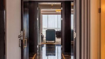 A hotel lobby with a polished marble floor, a reception desk, and a view of the lobby area through a glass door.