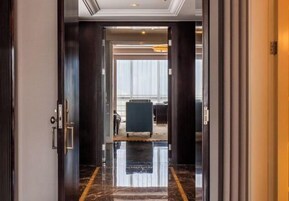 Vestíbulo de hotel con piso de mármol pulido, mostrador de recepción y vista al área del vestíbulo a través de una puerta de vidrio.