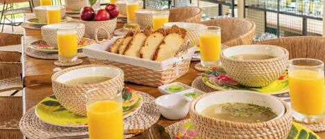 A breakfast setup with wicker baskets, bowls, and glasses of orange juice on a wooden table.
