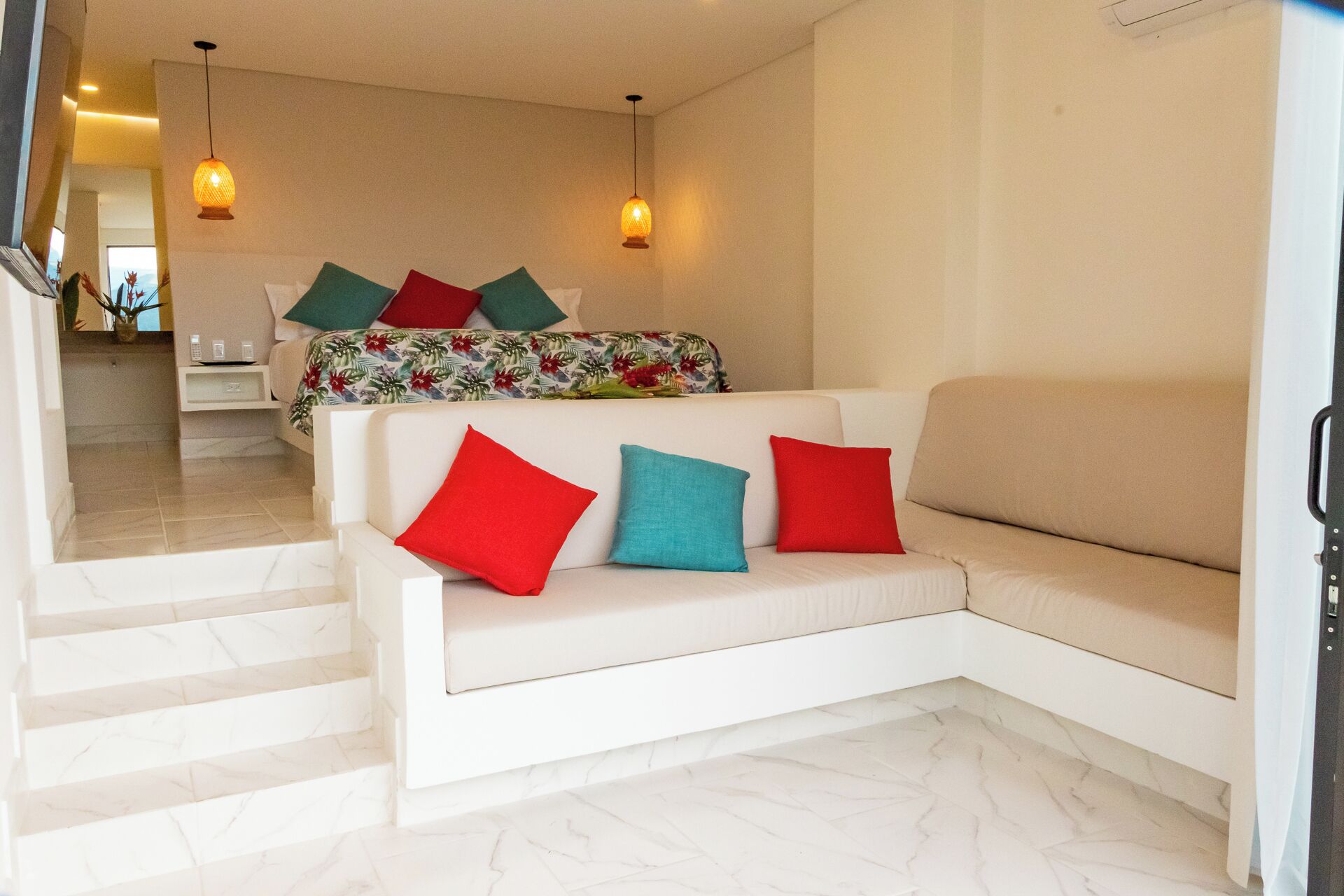 Un salon moderne avec un canapé blanc, des coussins colorés et un plaid à motifs.