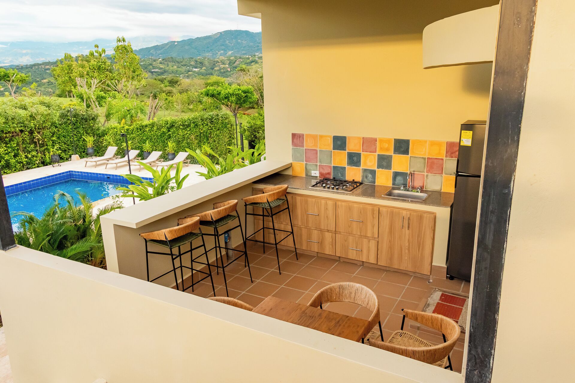 A kitchen with a view of a pool and mountains.