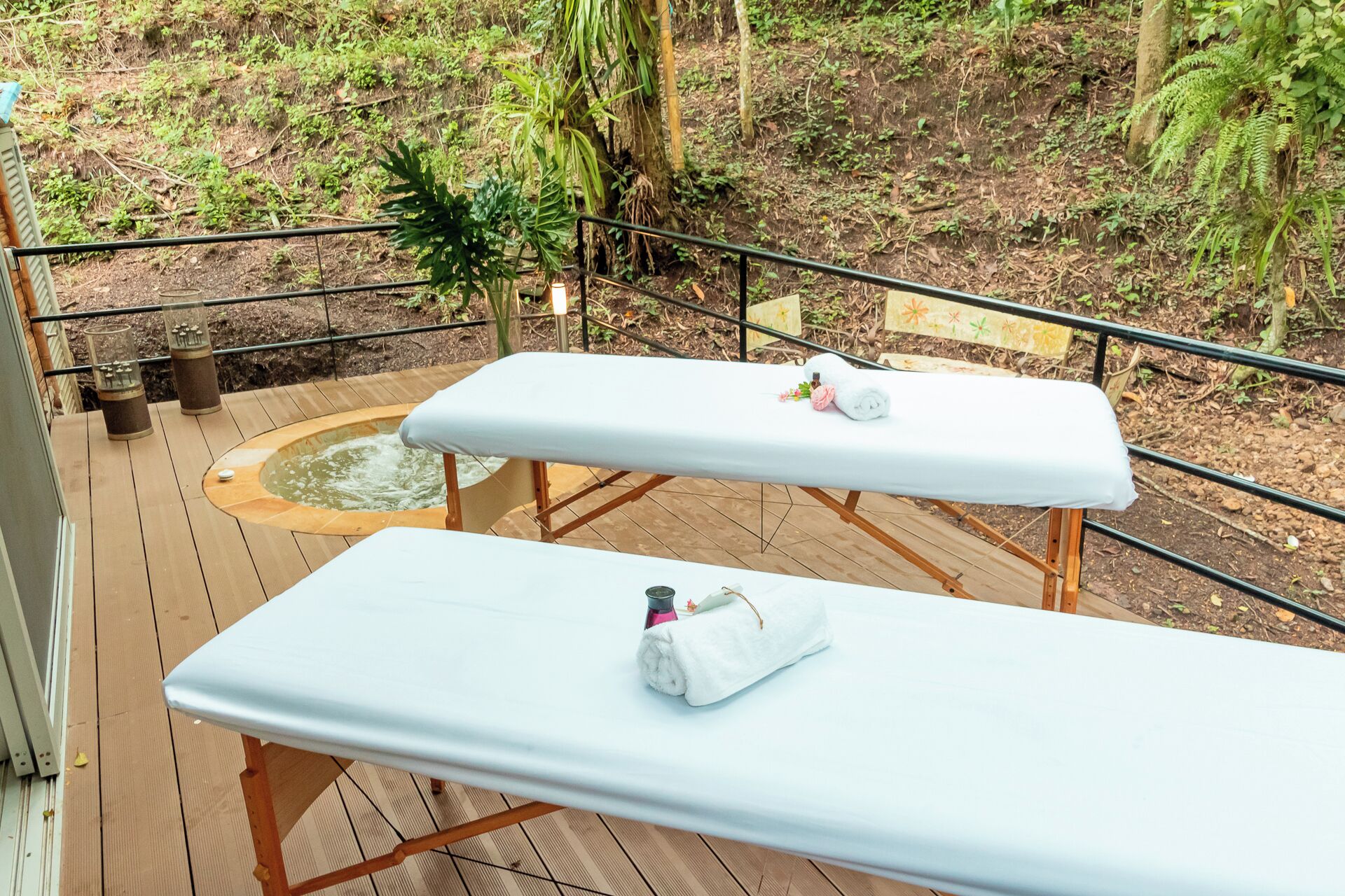 Two massage tables on a wooden deck with a hot tub and a bench in the background.