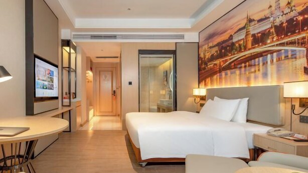 Une chambre d’hôtel avec un lit, une table de chevet, une lampe et un téléviseur posé sur un meuble.