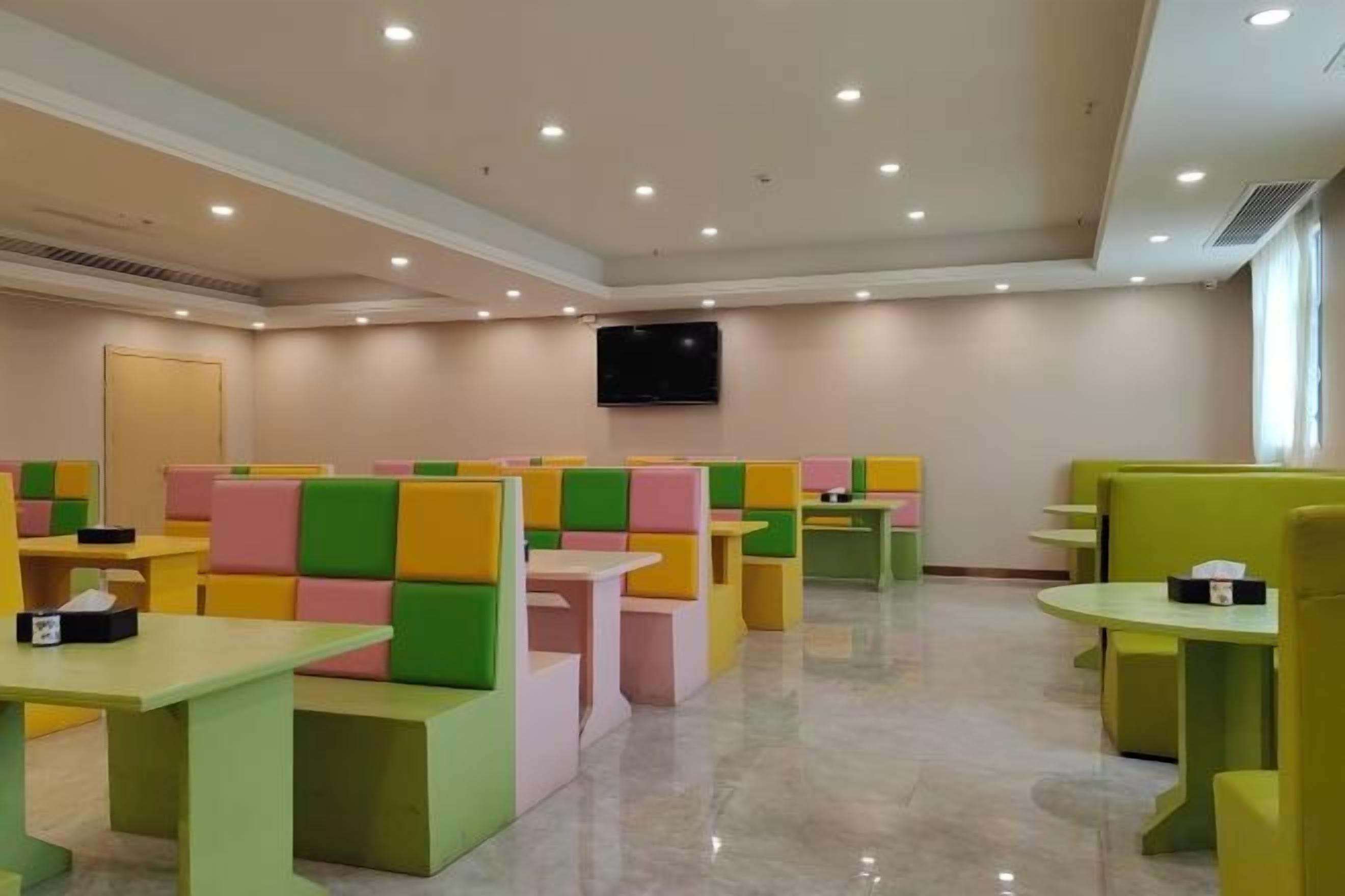 A restaurant with booths and tables, a flat-screen TV mounted on the wall, and a door in the background.