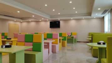A restaurant with booths and tables, a flat-screen TV mounted on the wall, and a door in the background.