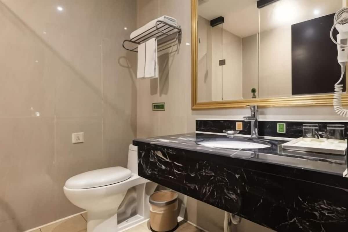 A modern bathroom with a white toilet, a black marble sink, a mirror, and a towel rack.