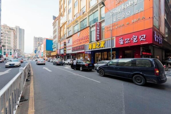 A street with multiple storefronts, including a prominent orange sign with Chinese characters. - Vienna Hotel (Dongguan Zhangmutou) (Dongguan)