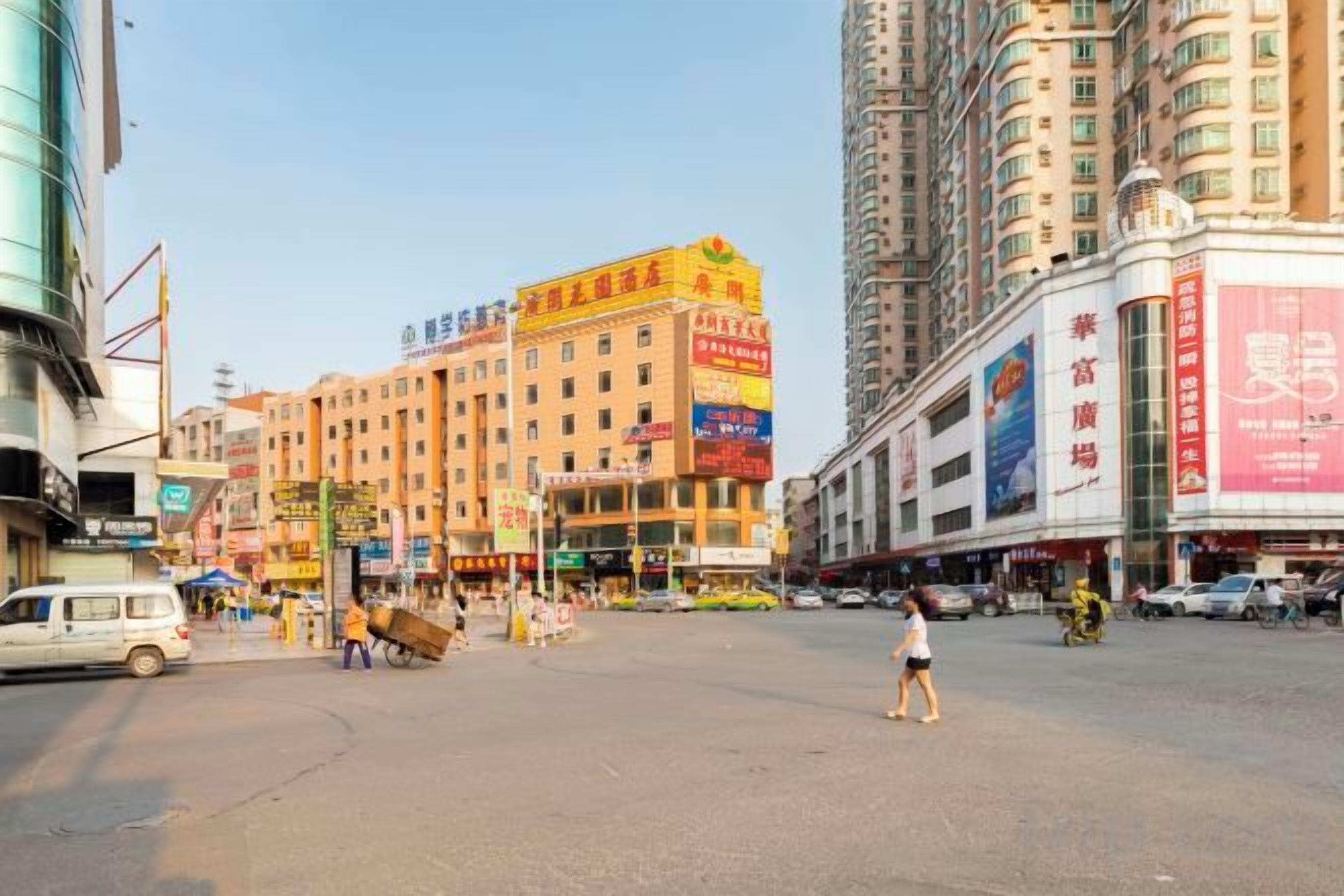 A busy urban street with high-rise buildings, shops, and a pedestrian crossing.