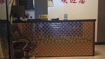 Un mostrador de recepción con un área de registro, una silla y una pared con diseño decorativo.