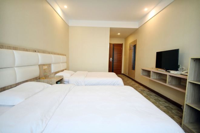 Habitación de hotel con dos camas, televisor y un escritorio pequeño con lámpara.