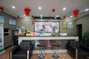 A reception area with a counter, two bar stools, and a seating area with two chairs.
