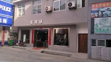 A building with a sign that reads 'POLICE' and another sign that says 'Guest House'. There are windows on the building, and a motorcycle is parked outside.