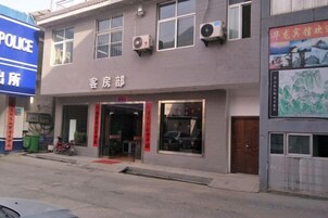 Un edificio con un cartel que dice 'POLICE' y otro que indica 'Guest House'. Hay ventanas en el edificio y una motocicleta estacionada afuera.