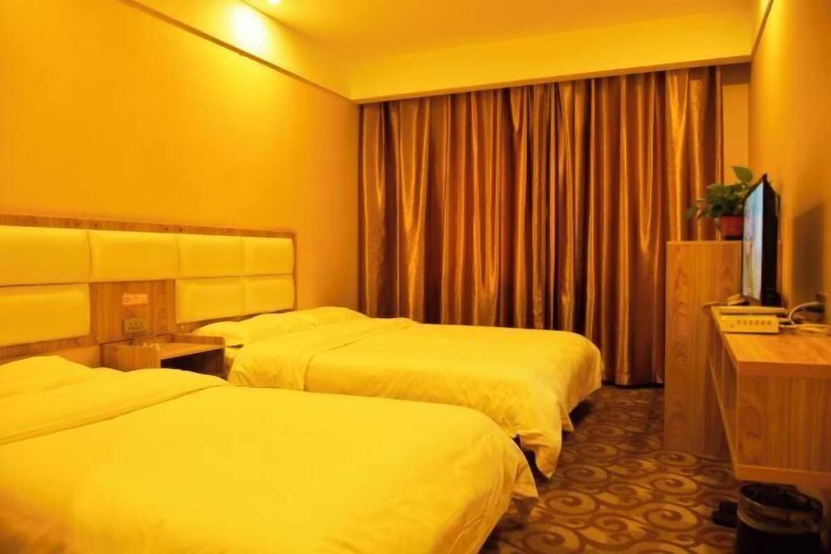 Een hotelkamer met twee bedden, een bureau, een televisie en een gordijn.