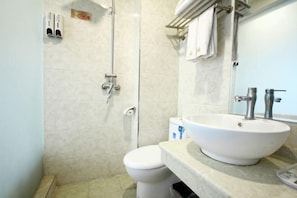 Un baño con inodoro, lavabo, espejo y ducha.