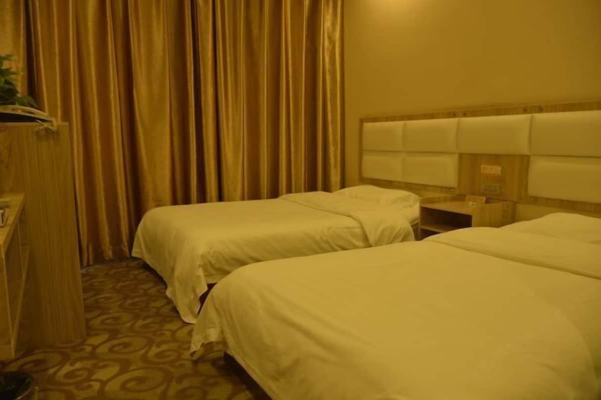 A hotel room with two beds, a wooden headboard, a nightstand, and a curtain.