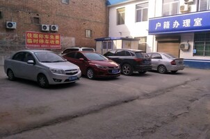 Una fila de coches estacionados frente a un edificio con un letrero azul que dice 'Hotel Management Office'.