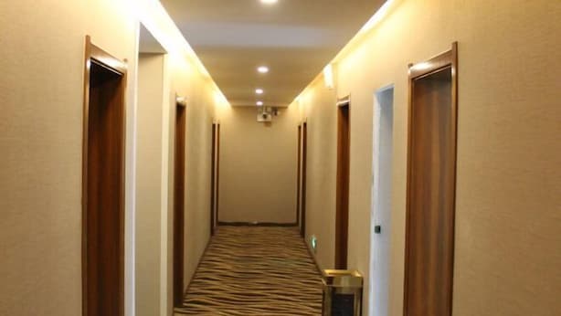 Un couloir d’hôtel avec un tapis à rayures zébrées, des portes en bois et un éclairage encastré.