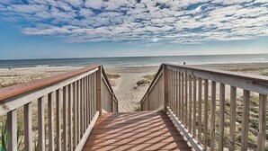 A wooden boardwalk leading to a beach with a clear sky and clouds. - Unforgettable Beachfront Bliss (Myrtle Beach)