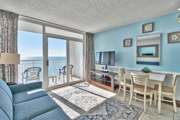 A room with a balcony, a TV, a desk, and a sofa. - Unforgettable Beachfront Bliss (Myrtle Beach)