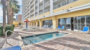 A hotel pool area with a clear pool, lounge chairs, and a palm tree. - Unforgettable Beachfront Bliss (Myrtle Beach)