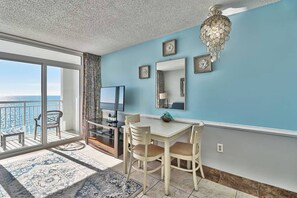 A room with a balcony, a TV, a dining table, and a chandelier. - Unforgettable Beachfront Bliss (Myrtle Beach)
