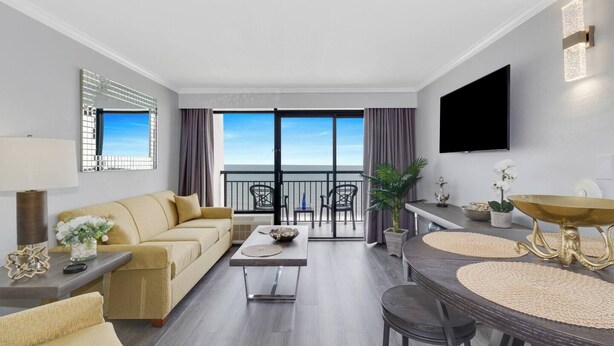 Une chambre d’hôtel moderne dotée d’un balcon, d’un canapé, d’une table à manger et d’un téléviseur.