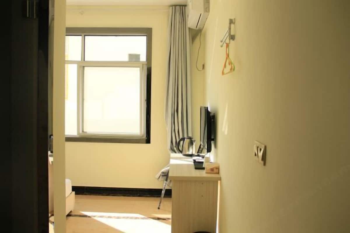 Ein Zimmer mit Fenster, Schreibtisch, Stuhl und Bett.