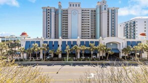 A large hotel with multiple floors, a central clock tower, and a parking lot in front. - Escape to the Ocean~ Oceanview Suite @CompassCove (Myrtle Beach)