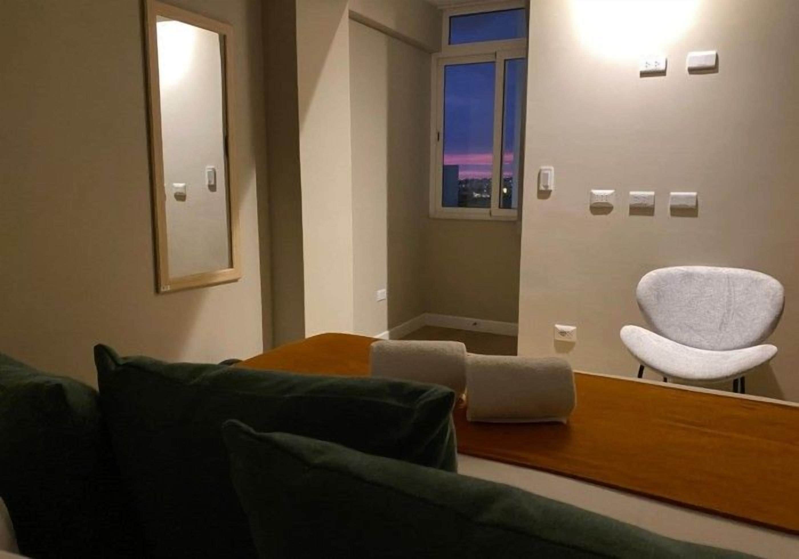 Habitación de hotel con cama, una silla, un ventanal y un espejo.